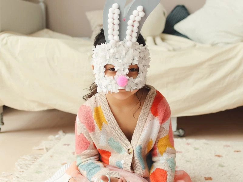 A child wearing a mask to resemble the Easter Bunny for the blog post titled, "Easter Activities for Toddlers."