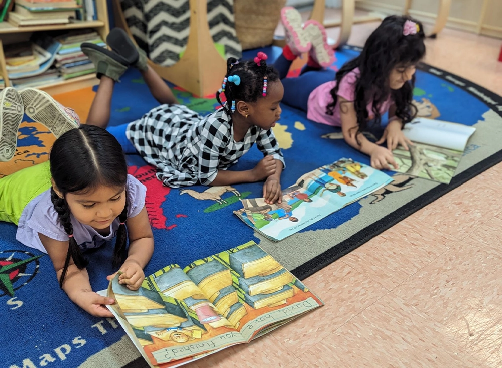 Children reading books on floor.