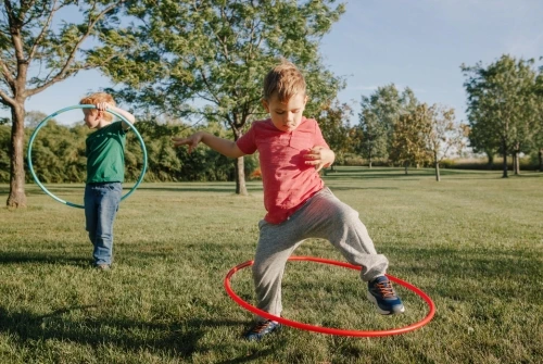 Two caucasian boys are playing with a hola hoop. This photo is intended for use with the blog titled, "Outdoor Activities for Preschoolers."