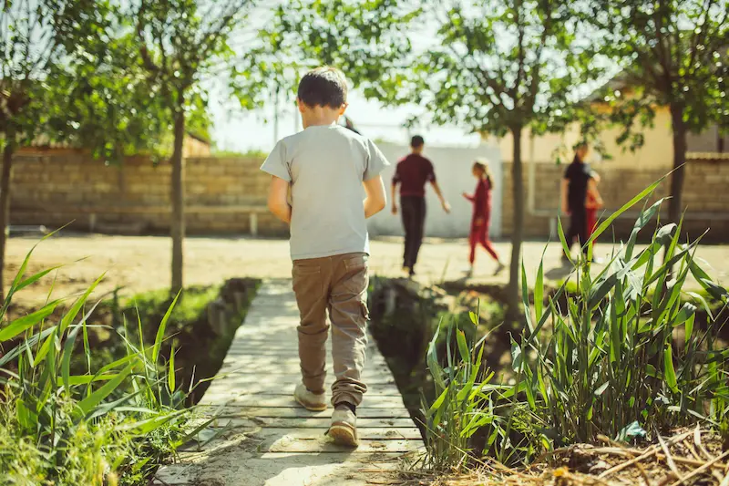 A male child is walking to meet a group of friends. This photo is for the blog post titled, "Road Safety for Kids."