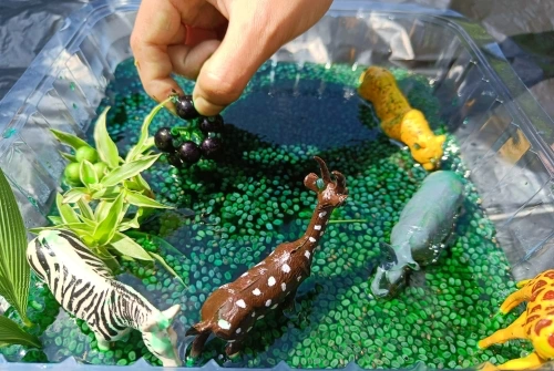 sensory activities for toddlers, like the bin filled with water and plastic animals shown in this image, can help your child learn and grow in a positive way.