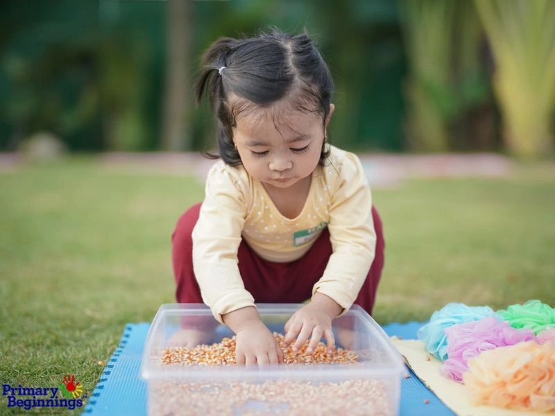 A young child playing in a sensory bin outside for the blog post titled "Easter Activities for Toddlers." 