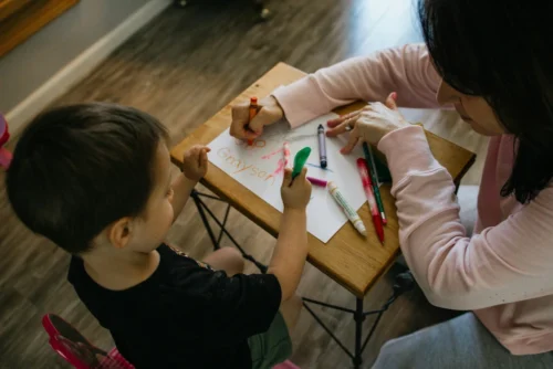 toddler care - child drawing with teacher